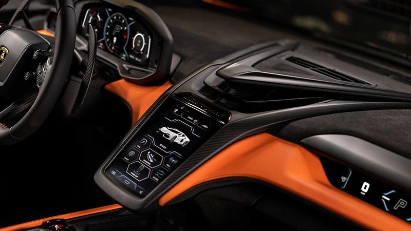 Trung tâm bảng điều khiển của Lamborghini Revuelto 2023 nổi bật với chi tiết cửa gió điều hòa với đường viền nổi hình tam giác phía trên, phía dưới là màn hình giải trí 8,4 inch đặt dọc gợi liên tưởng đến siêu xe McLaren. 